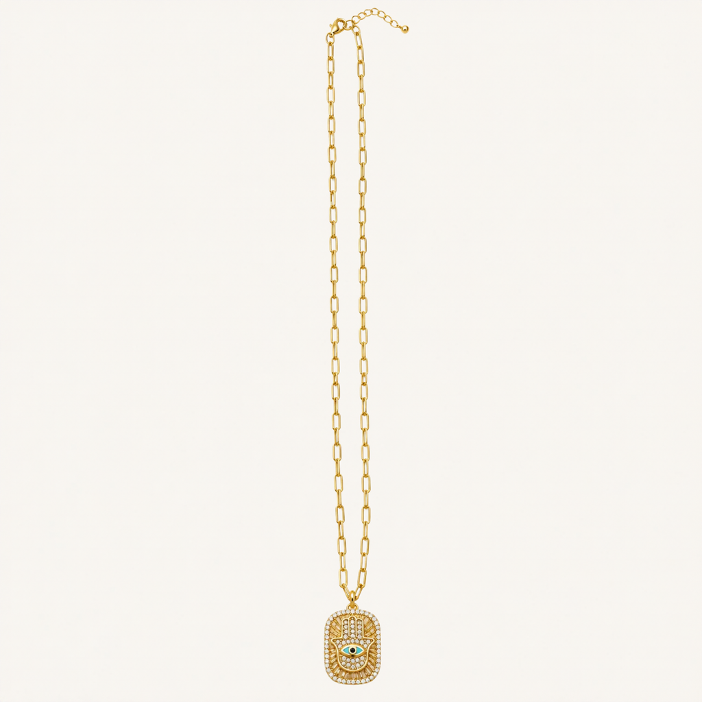 A gold chain necklace featuring a rectangular pendant encrusted with small clear stones and a central white stone, displayed against a solid off-white background.