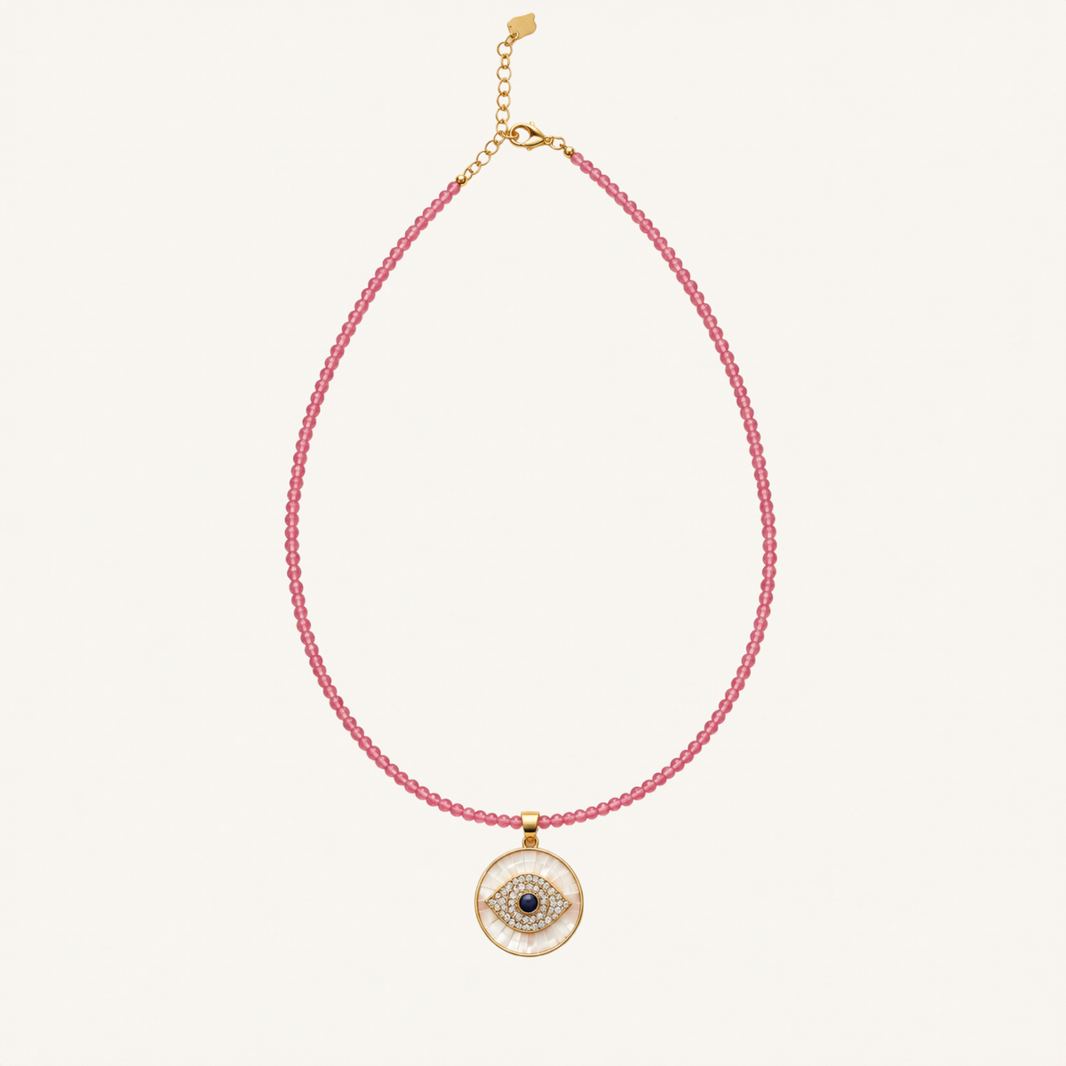 A pink beaded necklace with a gold-tone circular evil eye pendant, displayed on a clean off-white background.