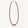 A black braided cord necklace with a gold-tone bar pendant featuring a pink enamel section with the word 'LOVE' and small gold details, shown on a light cream background.