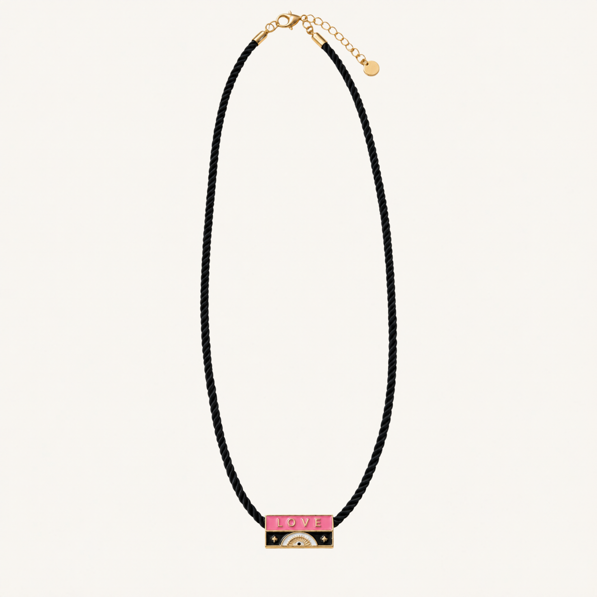 A black braided cord necklace with a gold-tone bar pendant featuring a pink enamel section with the word 'LOVE' and small gold details, shown on a light cream background.