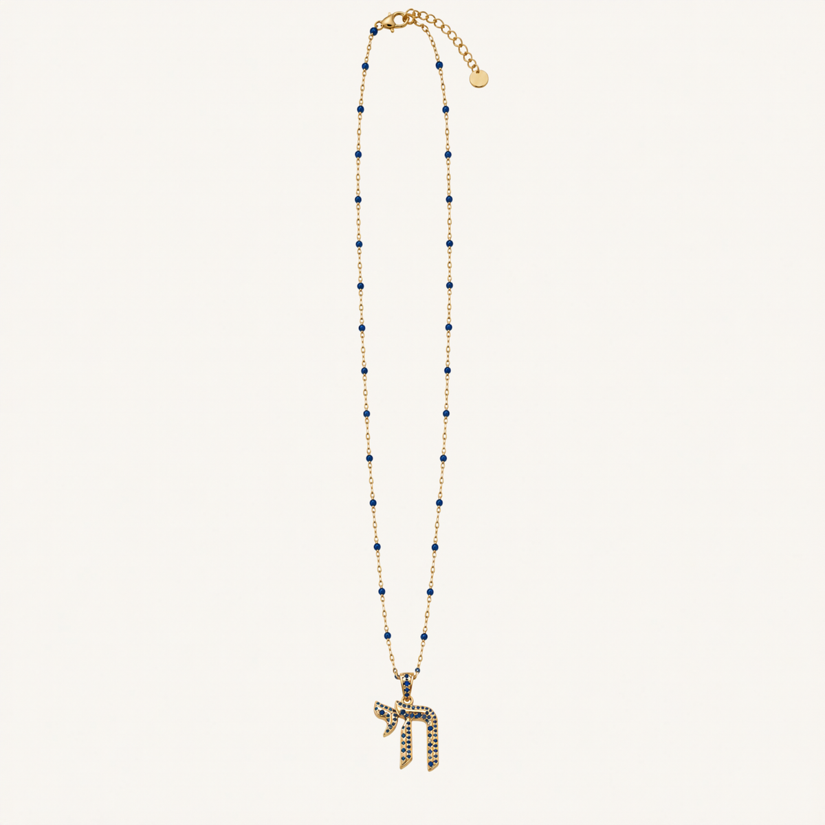 Gold-tone necklace with dark blue bead accents and a dark blue Chai pendant.
