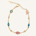 Gold chain bracelet with colorful enamel charms including a blue Star of David, pink Hamsa hand, blue fish, and teal Hamsa with a red dot, accented with small clear rhinestones on a light cream background.