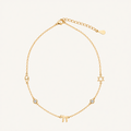 A delicate gold chain necklace featuring Hebrew letter charms, including a Pi symbol and a Star of David, with a small clear stone accent, displayed on a light cream background.