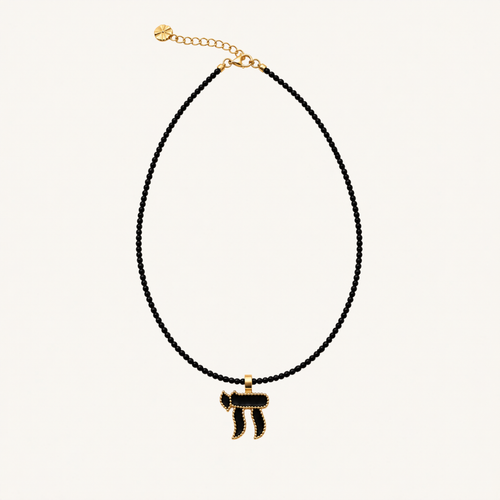 Black beaded necklace with a black Chai pendant edged in gold-tone metal.